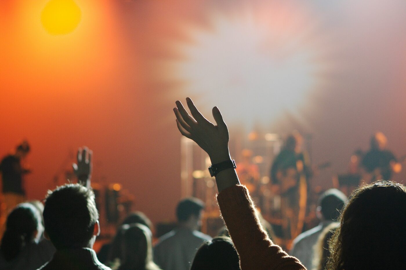 Worshippers raising their hands toward a brightly lit stage
